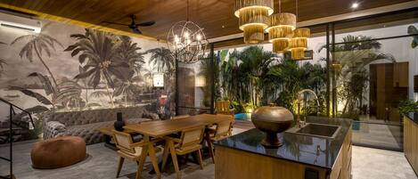 A modern kitchen with a large island, wooden furniture, and a mural of tropical scenery.