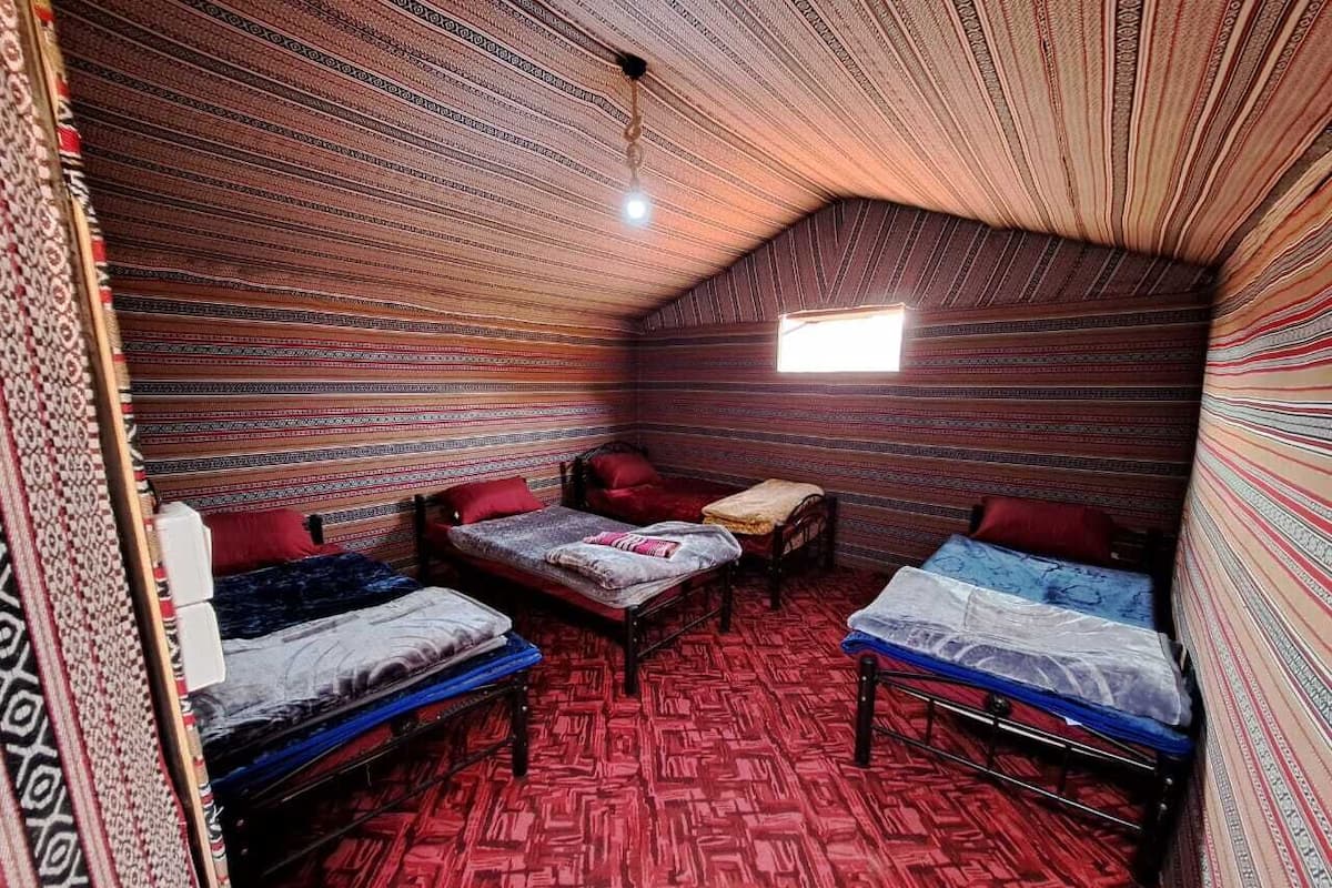 A room with three beds, a small table, and a window.