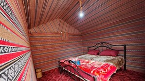 Una habitación con techo estampado, cama con colcha roja y beige, y alfombra roja.