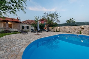A stone pool with lounge chairs and a stone wall.