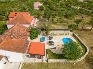 A residential property with a swimming pool, stone patio, and a garden area.