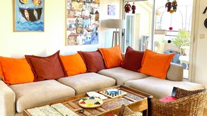 Ein Wohnzimmer mit einer Couch, zwei Sesseln, einem Couchtisch und einem Gemälde an der Wand.