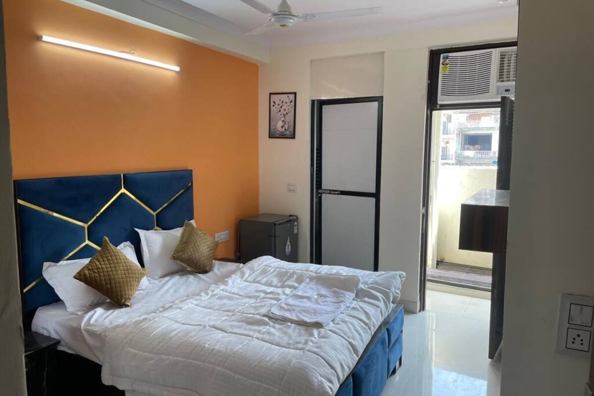 Una habitación de hotel con cama, escritorio, silla, ventilador de techo y ventana.