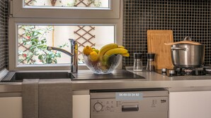 A kitchen with a sink, a bowl of fruit, a stove, and a window with a view of greenery. - New Paris Centre Historic Marrais Montorgueil Chic Suite Familiale 2 Bedrooms (Paris)