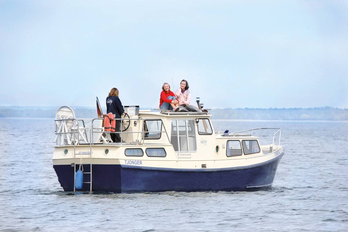 Ein Boot mit drei Personen, einer Leiter und einem Rettungsring.
