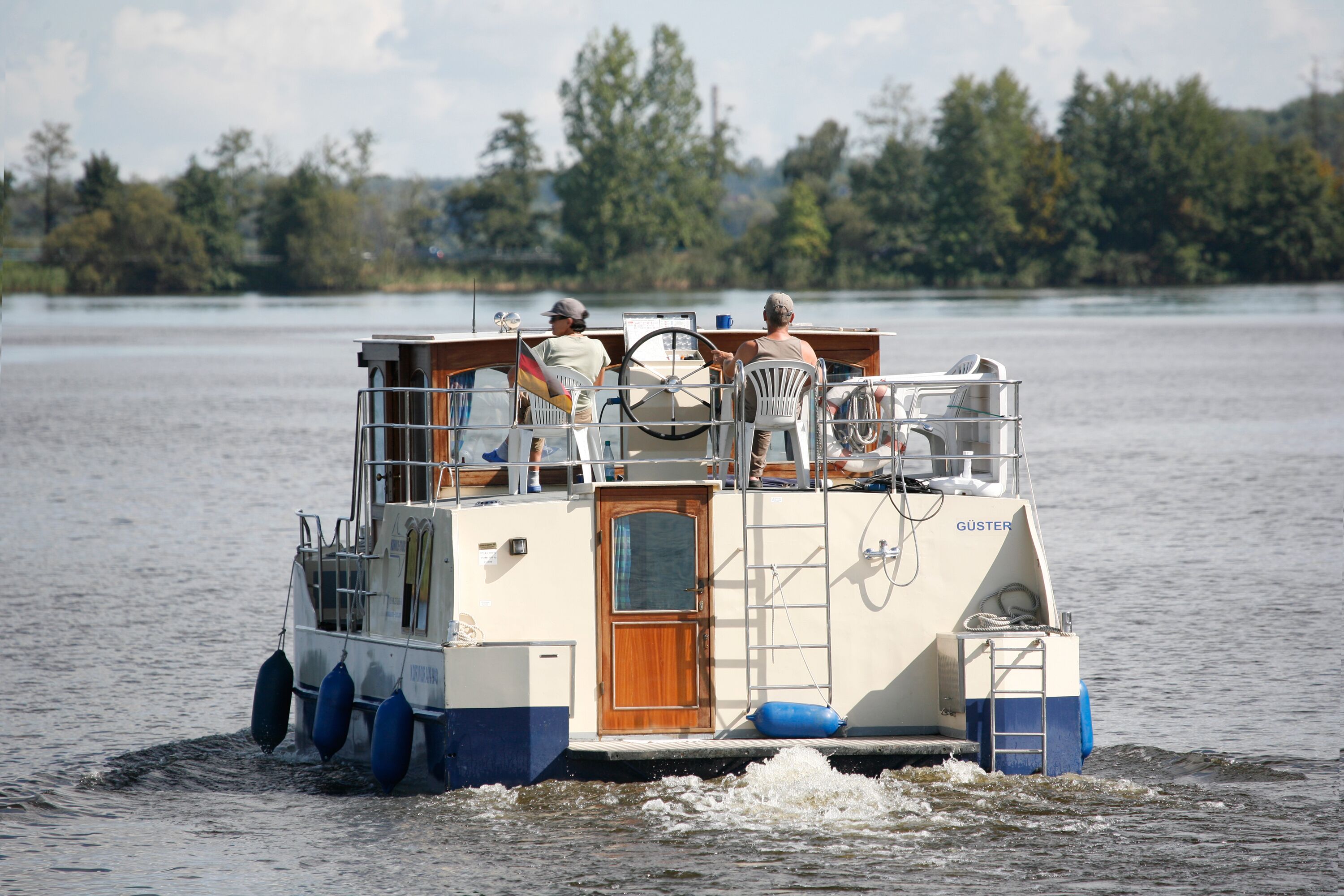 Ein Boot mit Holztür und Leiter, ausgestattet mit Steuerrad und Sitzgelegenheiten für Passagiere.