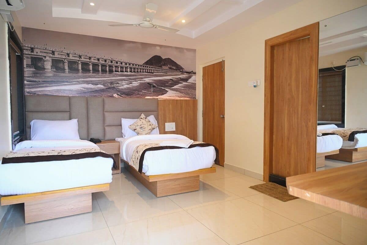 A modern hotel room with two beds, a large mural of a bridge, and a wooden door.
