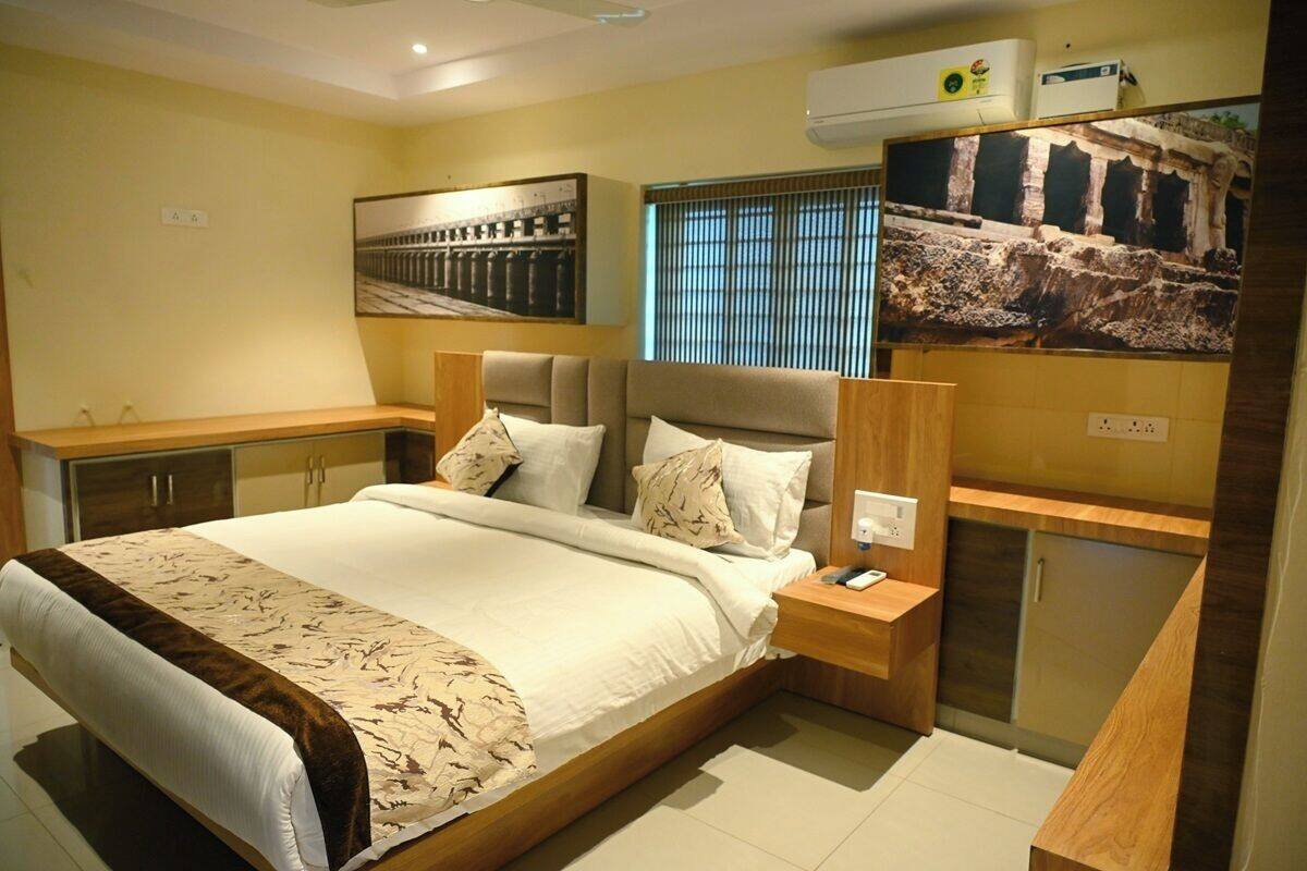 A modern bedroom with a large bed, wooden headboard, bedside tables, and a wardrobe.