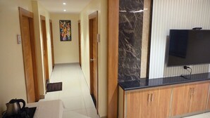Ein Hotelzimmer mit Holzschrank, Flachbildfernseher und Fliesenboden.