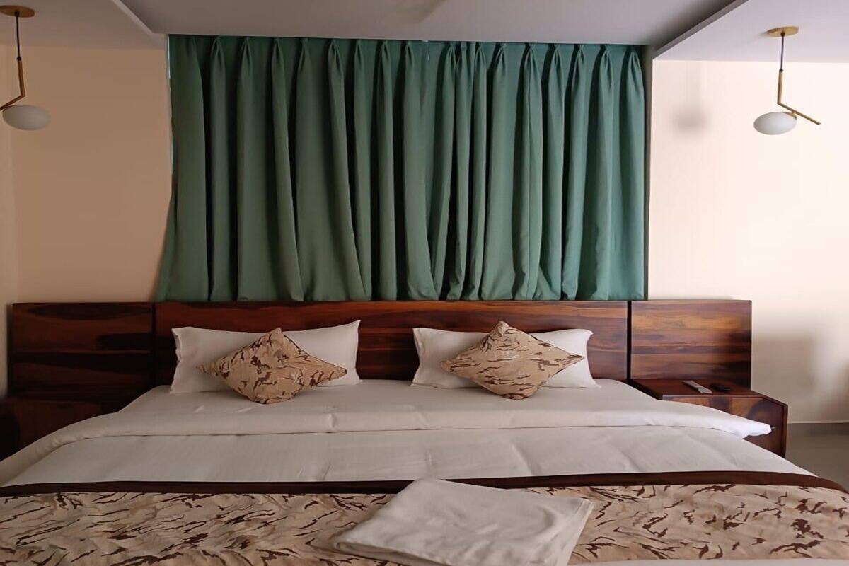 A neatly made bed with a wooden headboard, two decorative pillows, and a green curtain above.