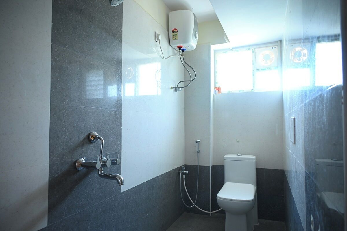 Een badkamer met toilet, douche en een aan de muur bevestigde boiler.