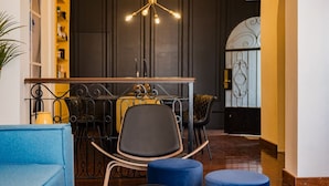 A modern interior with a dining area featuring a black metal table, a blue upholstered chair, and a unique ceiling light fixture. - Roma Retreat: Modern Colonial Gem A/C 16 PAX (Ciudad de México)