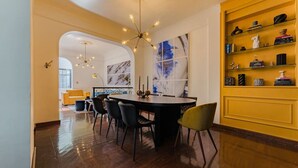 A modern dining area with a round table, black chairs, and a yellow accent wall. - Roma Retreat: Modern Colonial Gem A/C 16 PAX (Ciudad de México)