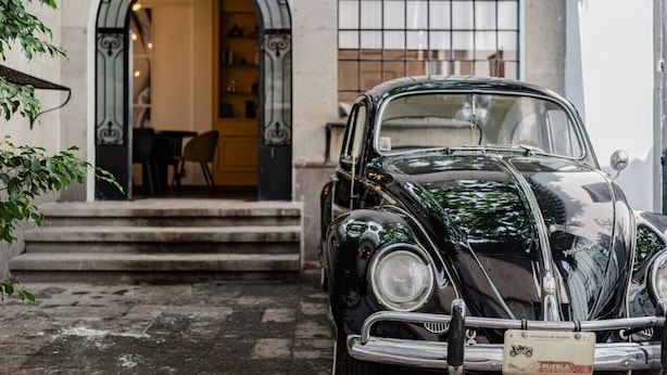 A vintage black car parked in front of a building with an arched entrance and a tiled window. - Roma Retreat: Modern Colonial Gem A/C 16 PAX (Ciudad de México)