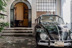 A vintage black car parked in front of a building with an arched entrance and a tiled window.