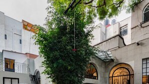 A vintage car parked in a courtyard with a stone floor, surrounded by buildings with arched windows and a staircase leading to a door. - Roma Retreat: Modern Colonial Gem A/C 16 PAX (Ciudad de México)