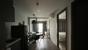 A modern hotel room with a kitchenette, a dining area, and a large bed. - 1 bed plus condo near JJ market (Bangkok)