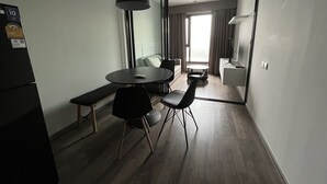 A modern hotel room with a dining area featuring a round table, two chairs, a bench, and a pendant light. - 1 bed plus condo near JJ market (Bangkok)
