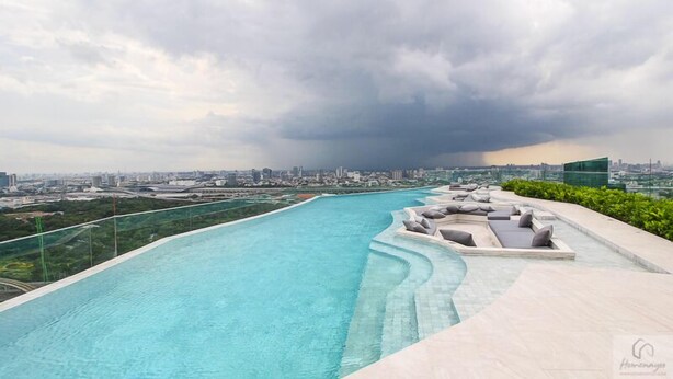 A rooftop infinity pool with a city view, surrounded by lounge seating and a glass barrier. - 1 bed plus condo near JJ market (Bangkok)