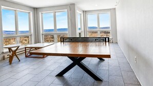 A spacious room with a large table, two chairs, and a bench. There are large windows offering a view of the landscape. - ML115 Lovely Slope Side Getaway Wi-Fi Parking Next to Village (Snowshoe)