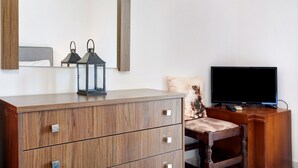 A wooden dresser with drawers, a television on a stand, and two lanterns on the dresser. - Studio Apartment "Yiannis 7" with Sea View, Shared Garden & Wi-Fi (Zakynthos)