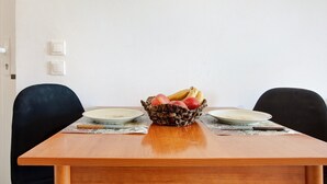 A dining table with a fruit basket, two plates, and a knife. - Studio Apartment "Yiannis 7" with Sea View, Shared Garden & Wi-Fi (Zakynthos)