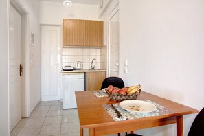 A dining area with a wooden table, a plate with food remnants, and a fruit basket.