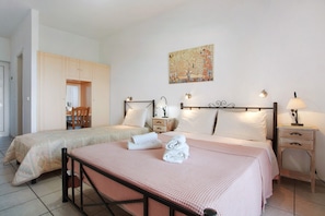A hotel room with two beds, a wooden wardrobe, a painting on the wall, and bedside lamps.