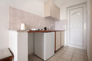A compact kitchen with a refrigerator, a coffee maker, and a sink.