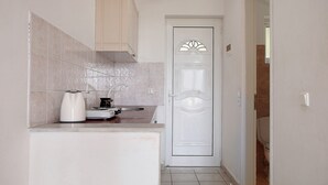 Une petite cuisine avec une porte blanche, une machine à café et un évier.