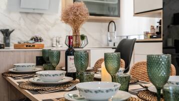 Una mesa de comedor dispuesta con cristalería verde, una botella de vino y una vela.