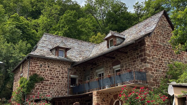 A stone house with a balcony, a small window, and a gate. - Holiday Home "Gîte Le Pressoir Domaine de Jouani" with Shared Pool & A/C (villecomtal)