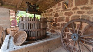 A stone wall, a wooden barrel, and a large wheel. - Holiday Home "Gîte Le Pressoir Domaine de Jouani" with Shared Pool & A/C (villecomtal)