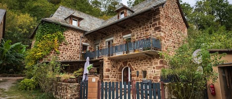 A stone building with a balcony, a gate, and a fire extinguisher.