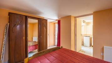 A bedroom with a bed, a wardrobe, and a bathroom visible through an open door.