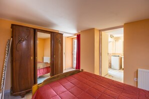 Une chambre à coucher avec un lit, une armoire et une salle de bain visible à travers une porte ouverte.