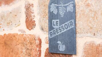 A metal plaque with the inscription 'LE PRESSOIR' and an apple symbol, mounted on a stone wall.