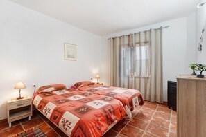 Un dormitorio con cama, lámparas de noche, un escritorio y una ventana con cortinas.