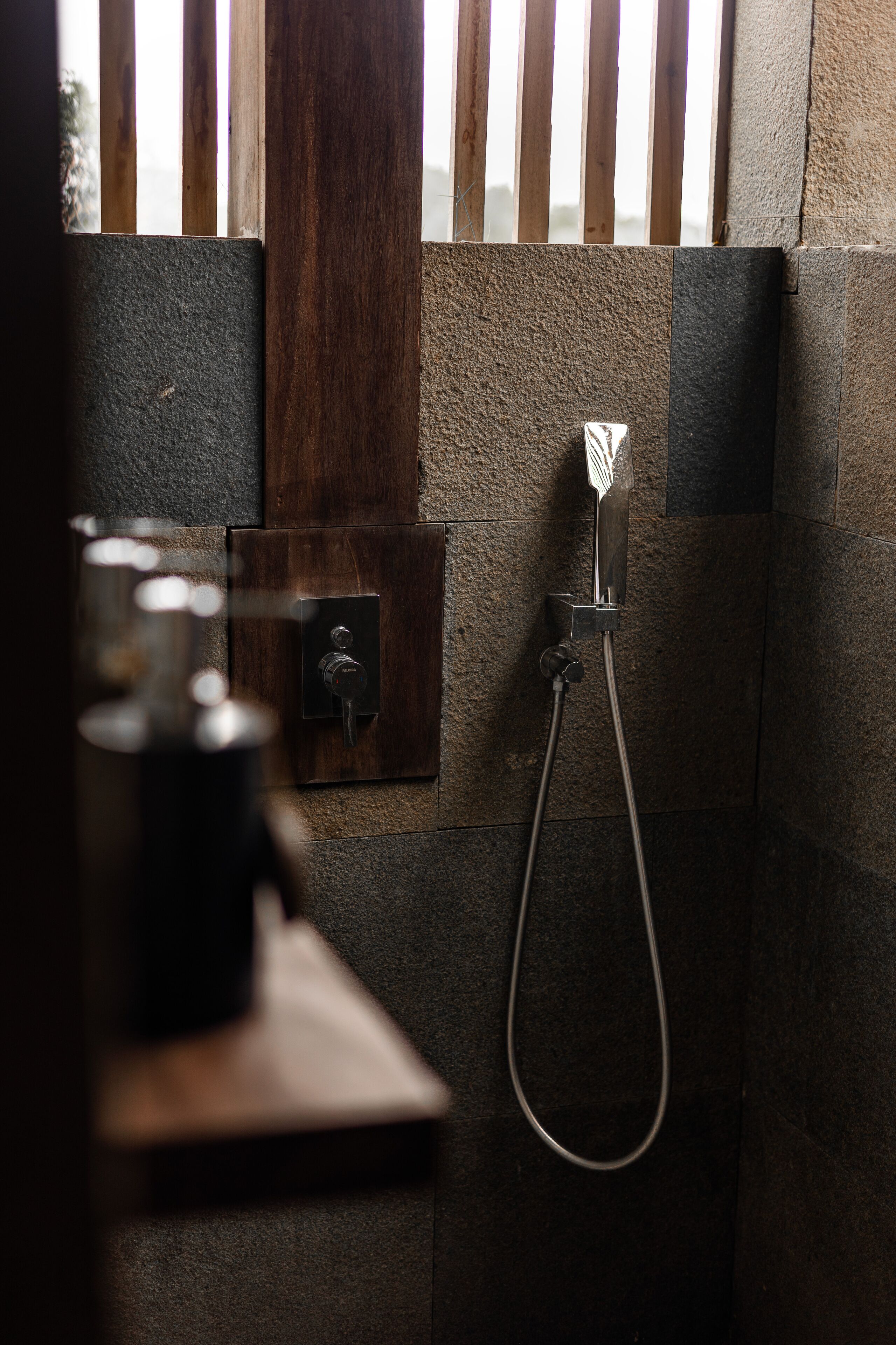 A bathroom with a shower, a towel rack, and a glass of water on a counter.