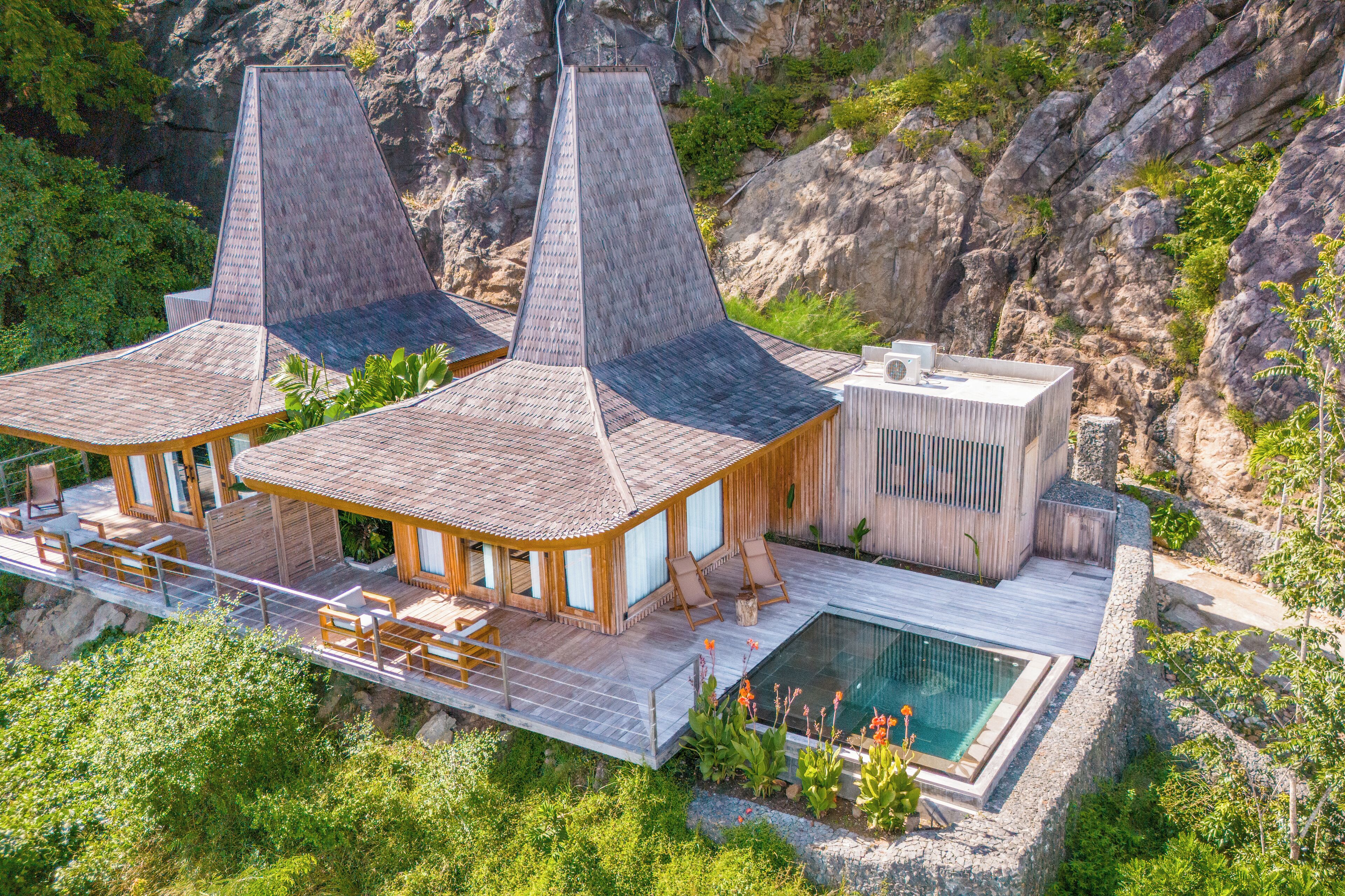 A modern resort with two large buildings, a pool, and a wooden deck.