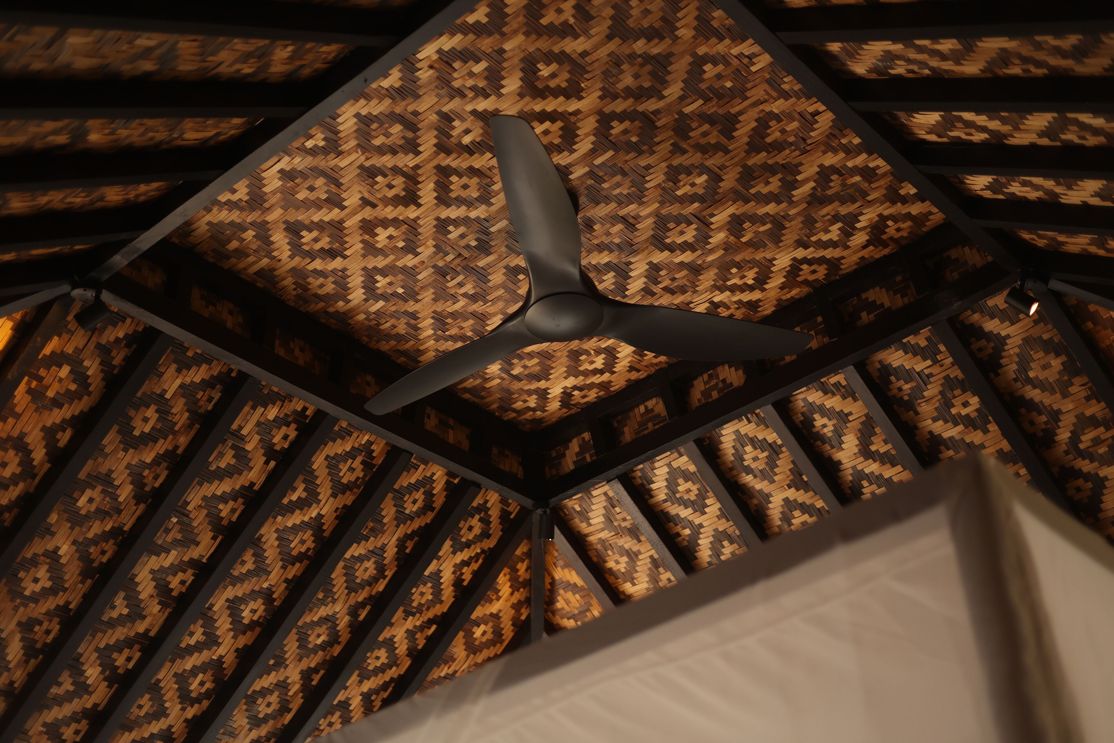 A ceiling fan in a room with a patterned wall.
