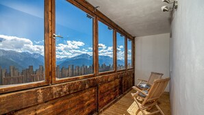 Ein Balkon mit Holzgeländern, Holzboden und zwei Korbstühlen.