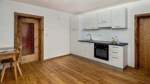 Eine Küche mit weißen Schränken, einem schwarzen Backofen und einem Holzespeisesaal mit Stühlen.