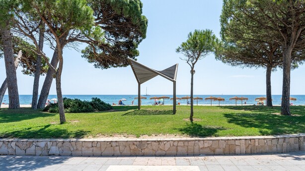 Un parc avec un banc en pierre, des arbres et une vue sur la mer.