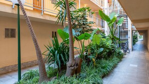 Un immeuble à plusieurs étages doté de balcons, d’une galerie couverte et de plantes d’intérieur.