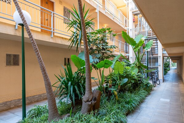 A multi-level building with balconies, a covered walkway, and indoor plants.
