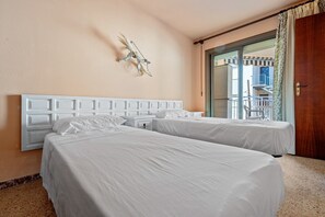 Ein Hotelzimmer mit zwei Betten, einem weißen Kopfstück, einer Wanddekoration und Blick nach draußen.