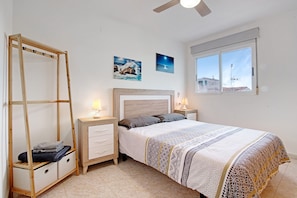 A bedroom with a bed, nightstands, a wooden wardrobe, and a window with a view.