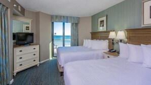 A hotel room with two beds, a television on a dresser, a nightstand with lamps, and a view of the ocean. - Oceanfront Deluxe Serenity (Myrtle Beach)