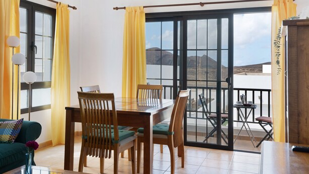 Un espace repas comprenant une table et des chaises, un canapé et une vue sur l’extérieur grâce à une porte-fenêtre coulissante.